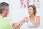 Doctor examining his patients arm in medical office