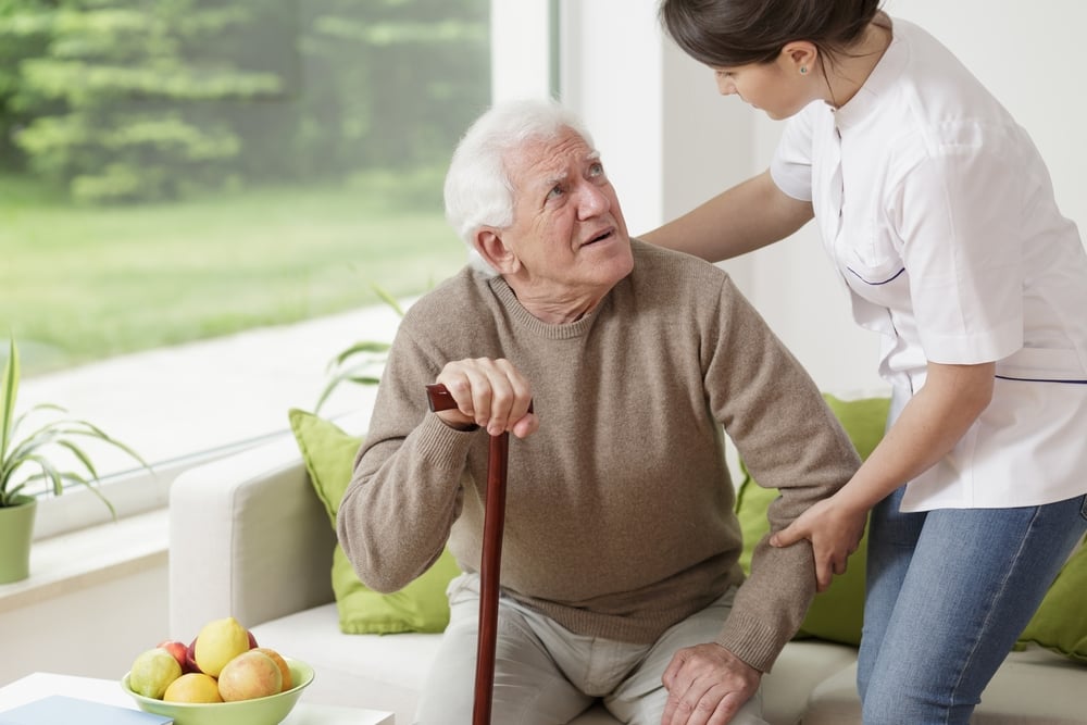 Young woman helping old man to stand up